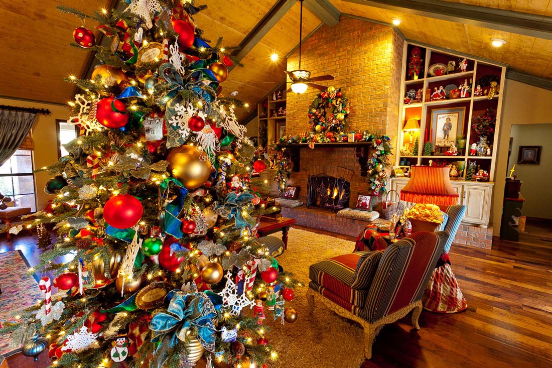 Kolorowa, bogato ustrojona choinka świąteczna udekorowana czerwonymi i złotymi bombkami, niebieskimi wstążkami oraz innymi pomysłowymi ozdobami