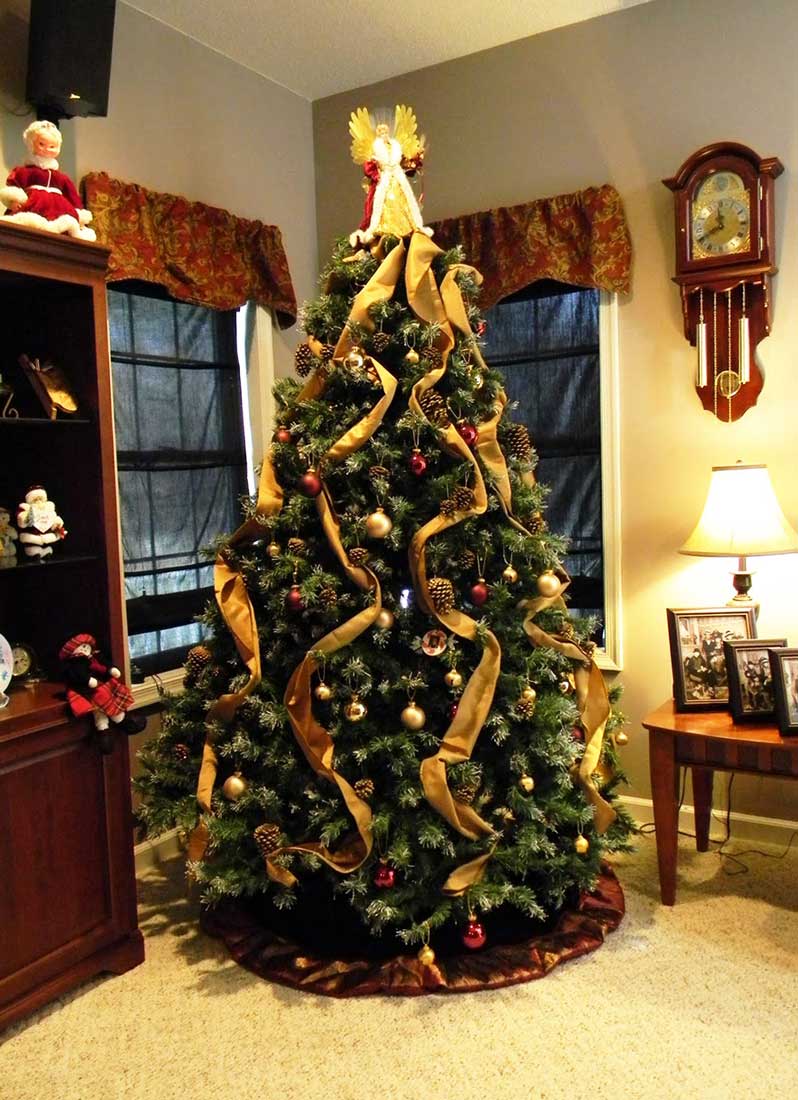 Ładna, gustowna choinka na Boże Narodzenie ozdobiona złotymi szarfami, wstążkami, bombkami oraz świerkowymi szyszkami