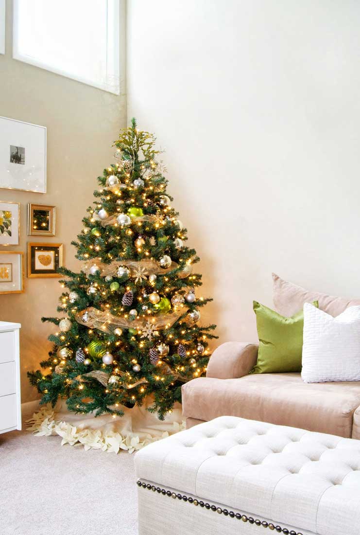 Pomysł jak ubrać choinkę na święta - skromne drzewko w domu, srebrne, złote i zielone bombki oraz szyszki